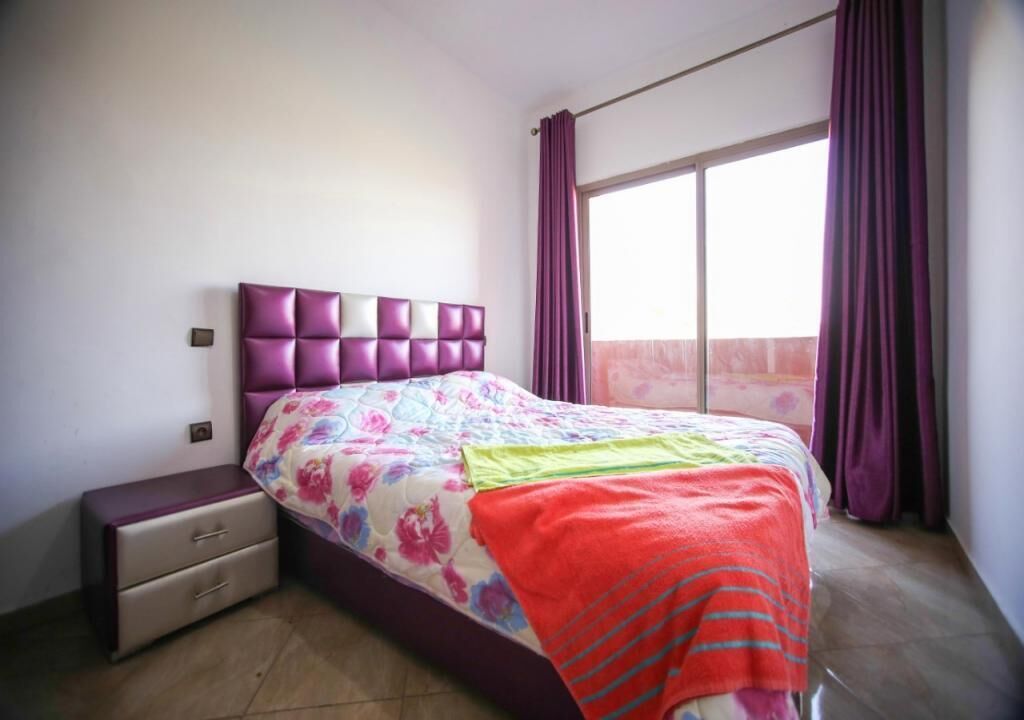 Un dormitori amb llit, una vetust i cortines, i vista a l'exterior.