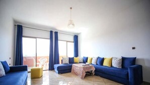 A living room with a blue sofa set, a yellow ottoman, and a patterned coffee table. - Zahoui Garden Marrakech 4761 (Marrakech)