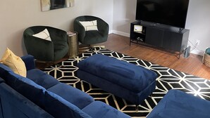 En stue med en blå sofa, et sort TV-bord og en loftsvift.