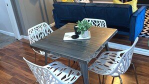 A dining area with a table and chairs, a blue sofa, a TV, and a clock on the wall. - ~Chandler’s Chateau in the Heart of Brevard ~ (Brevard)