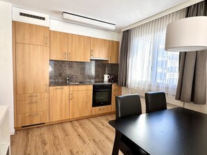 Eine moderne Küche mit Holzausstattung, einer schwarzen Arbeitsplatte und einem Essbereich mit Tisch und Stühlen.