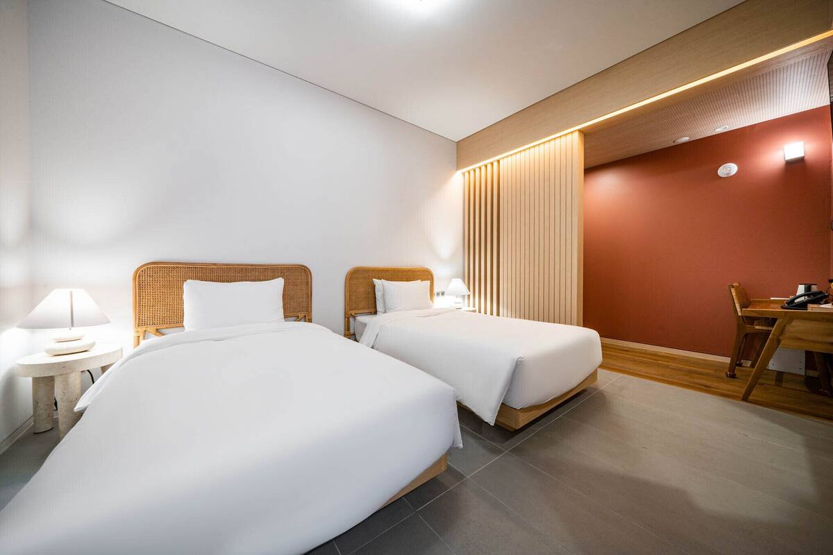 A hotel room with two beds, a desk, and a chair.