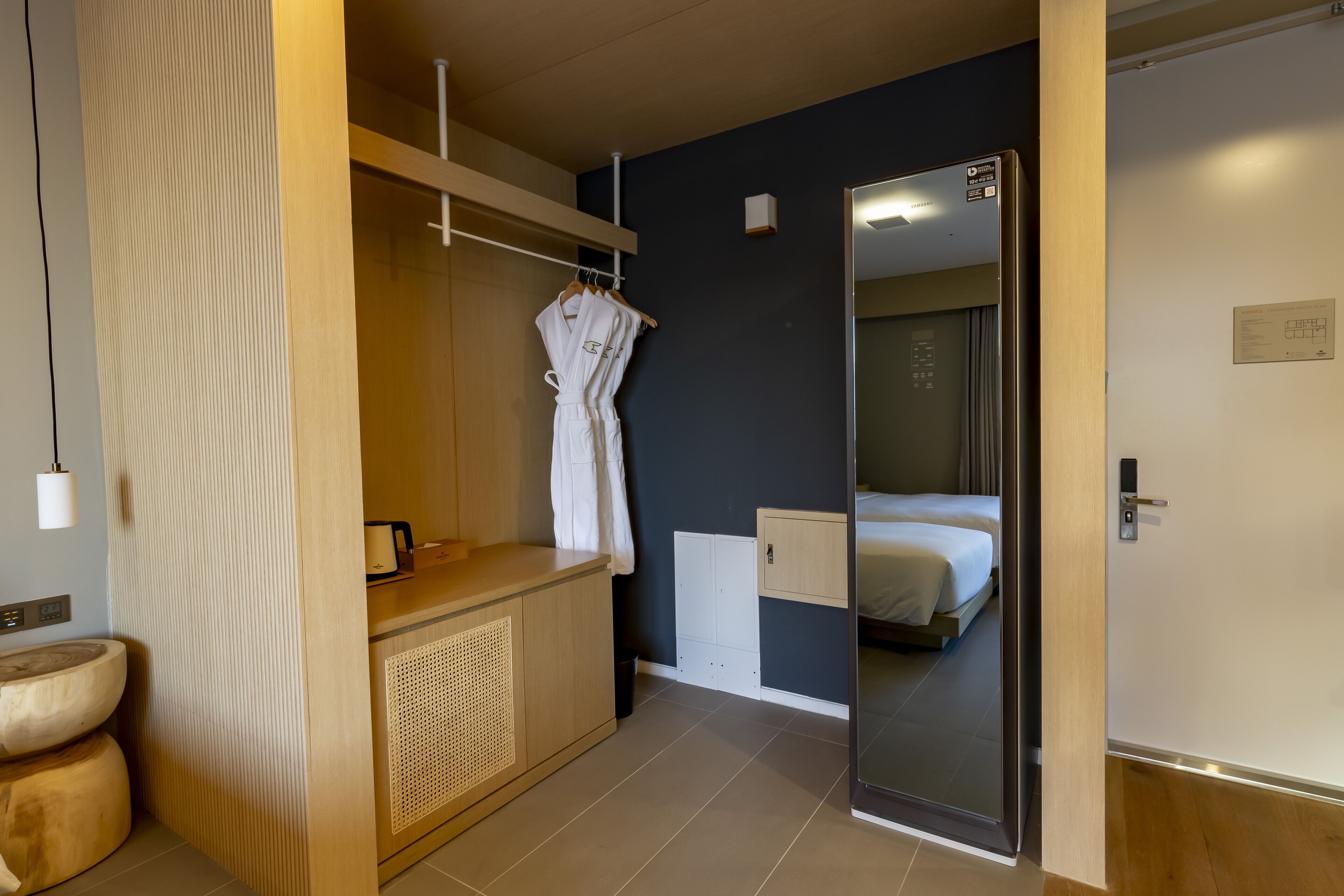 Een moderne hotelkamer met een houten wastafel, een spiegel, een bed en een kledingkast.