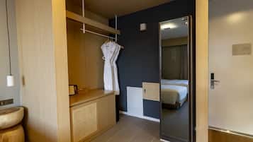 Een moderne hotelkamer met een houten wastafel, een spiegel, een bed en een kledingkast.