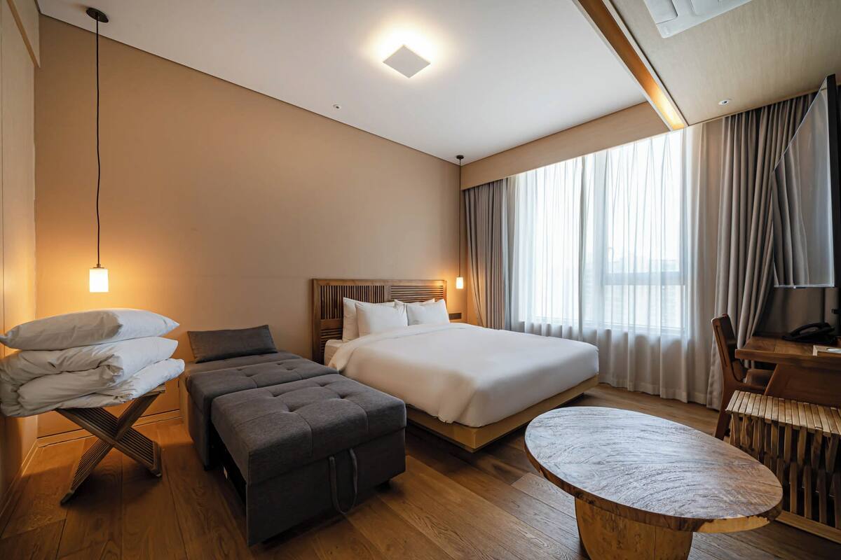 A hotel room with a bed, a sofa, a small table, and a desk.