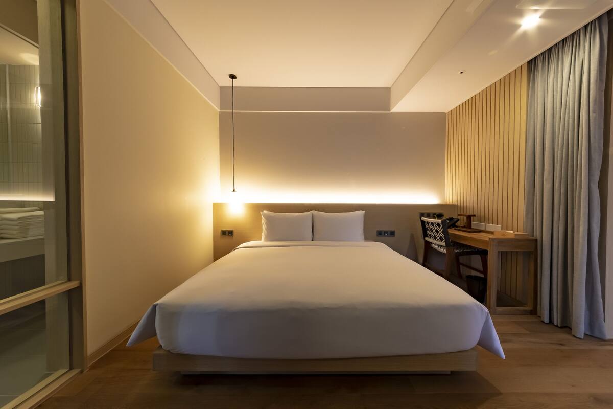 A modern hotel room with a large bed, a desk, and a chair.