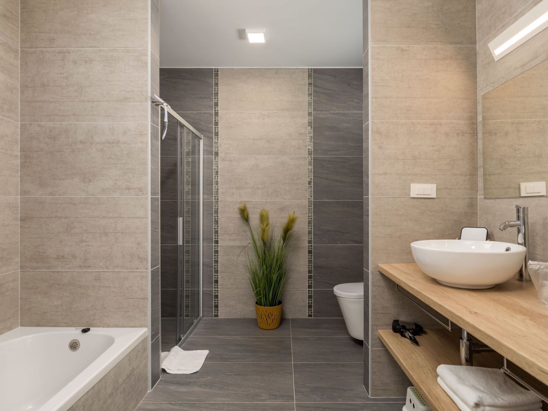 Une salle de bain moderne équipée d’une baignoire, d’une douche à parois de verre, d’un lavabo avec un grand bac et de toilettes.