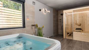 Relax in a spacious bathroom with a large hot tub and sauna, offering a serene retreat.