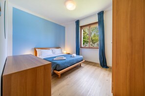 Ein Schlafzimmer mit einem Bett, einem Nachttisch und einem Fenster mit Vorhängen.