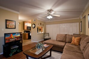 A living room with a television, sofa, coffee table, and a ceiling fan.