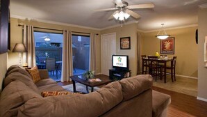 Una sala de estar con sofá, mesa de centro, televisor y comedor con mesa y sillas.