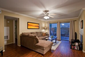 Una sala de estar con sofá, mesa de centro, mueble para televisor y ventilador de techo.
