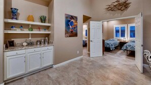 A spacious hallway with a kitchen area, a dining area, and a bedroom with a window. - Harmony Haven! Your Artful Escape (Scottsdale)