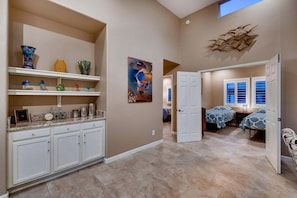 A spacious hallway with a kitchen area, a dining area, and a bedroom with a window.