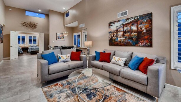 A spacious living room with two grey sofas, a glass coffee table, and a large painting on the wall. - Harmony Haven! Your Artful Escape (Scottsdale)