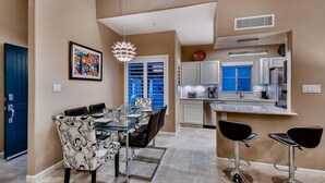 A modern kitchen with a dining area, featuring a glass table, black chairs, and a unique pendant light. - Harmony Haven! Your Artful Escape (Scottsdale)