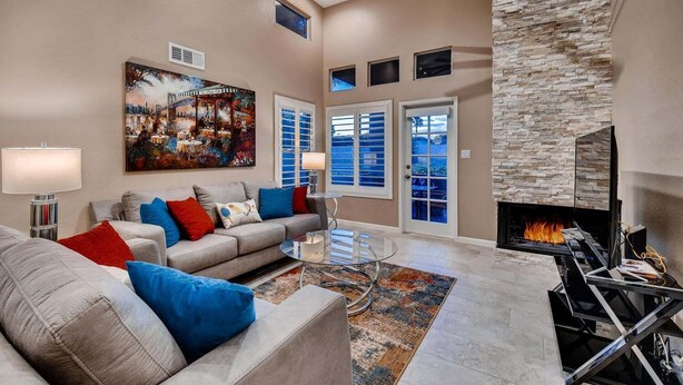 A living room with a fireplace, a sofa set, a painting, and a stone accent wall. - Harmony Haven! Your Artful Escape (Scottsdale)