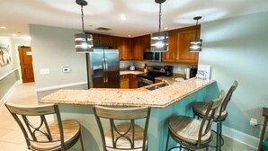 Uma cozinha com ilha central, banquetas e eletrodomésticos modernos.