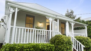 A white wooden house with a porch, a staircase, and a well-maintained hedge. - Sierra Cottage (East Toowoomba)