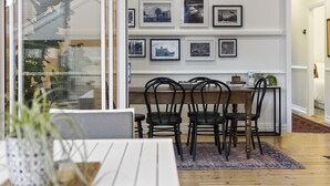 A dining area with a wooden table and chairs, a patterned rug, and a wall with framed pictures. - Sierra Cottage (East Toowoomba)