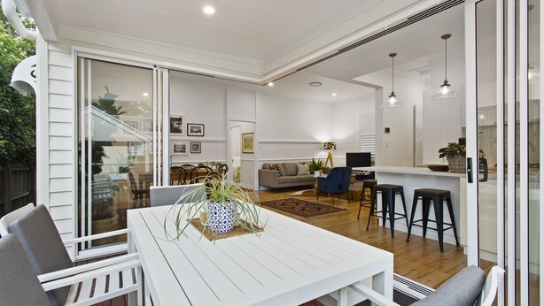 A spacious patio with a white table and chairs, a blue sofa, and a kitchen area with stools. - Sierra Cottage (East Toowoomba)