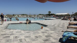 A swimming pool area with multiple pools, sun loungers, and a tiled deck. - Peek of the ocean King size bed just Steps from the Beach (Hilton Head Island)