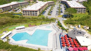 An aerial view of a hotel with a large swimming pool, multiple parking lots, and several buildings with balconies. - Peek of the ocean King size bed just Steps from the Beach (Hilton Head Island)