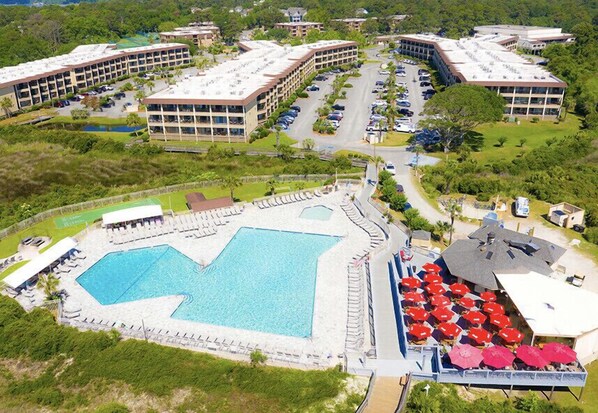 Une vue aérienne d’un hôtel doté d’une grande piscine, de plusieurs parkings et de plusieurs bâtiments avec des balcons.