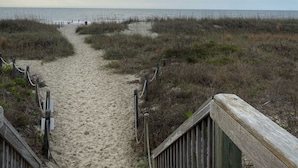 A sandy beach path leading to the ocean, surrounded by grassy dunes and wooden boardwalks. - Peek of the ocean King size bed just Steps from the Beach (Hilton Head Island)