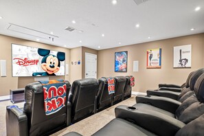 A conference room with multiple black leather chairs, a large Disney Mickey Mouse poster, and movie posters on the walls.