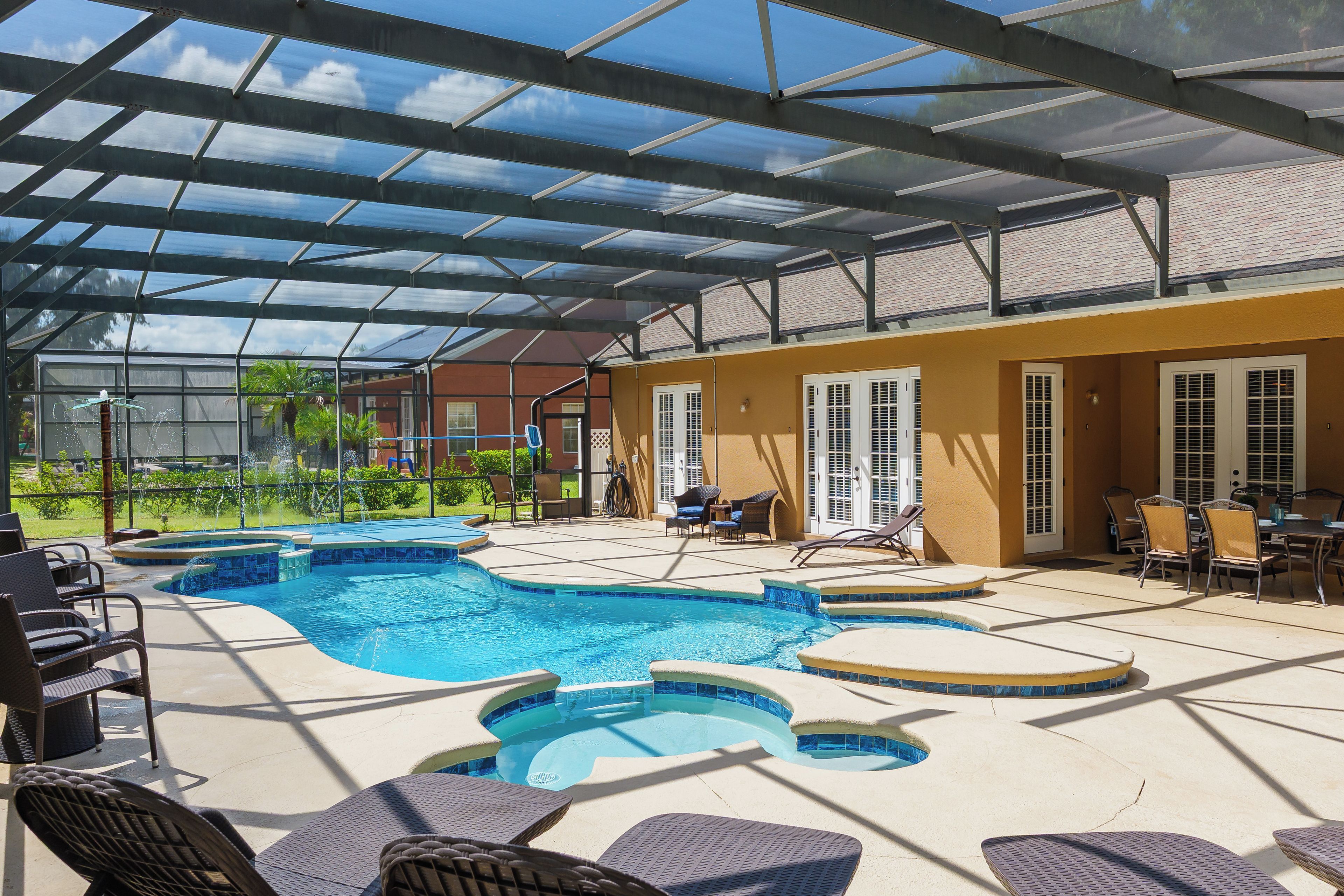 A covered outdoor swimming pool with lounge chairs and a patio area.