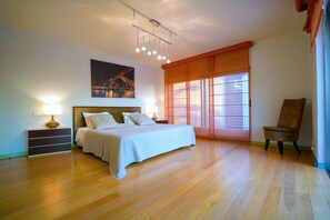 Relax in this serene bedroom with a large bed, nightstand, and comfortable chair.