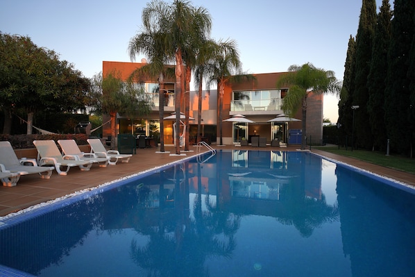Relax by the serene pool surrounded by lush greenery and modern architecture.