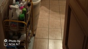 Een kleine, smalle badkamer met een wasmachine, een wastafel en diverse toiletartikelen.