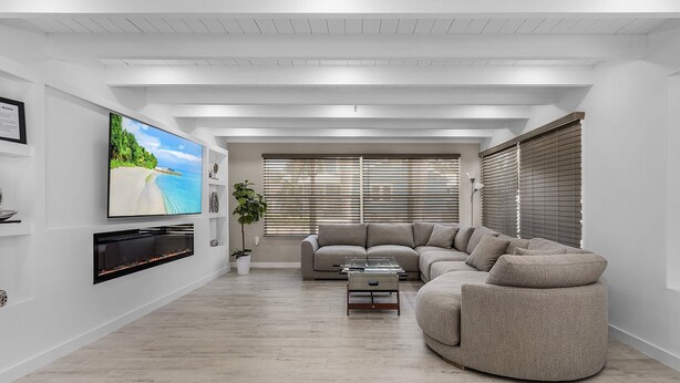 A modern living room with a sectional sofa, a flat-screen TV mounted on the wall, and a fireplace. - Downtown Retreat (Fort Myers)