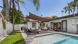 A swimming pool with a sunshade, outdoor seating, and a white fence. - Downtown Retreat (Fort Myers)