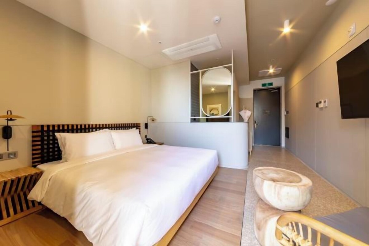 Ein Hotelzimmer mit einem großen Bett, einem Nachttisch, einem Stuhl und einem Spiegel.