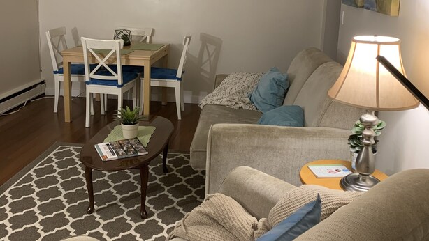 Una sala de estar con un sofá, una mesa de centro, una mesa de comedor con sillas y una lámpara.