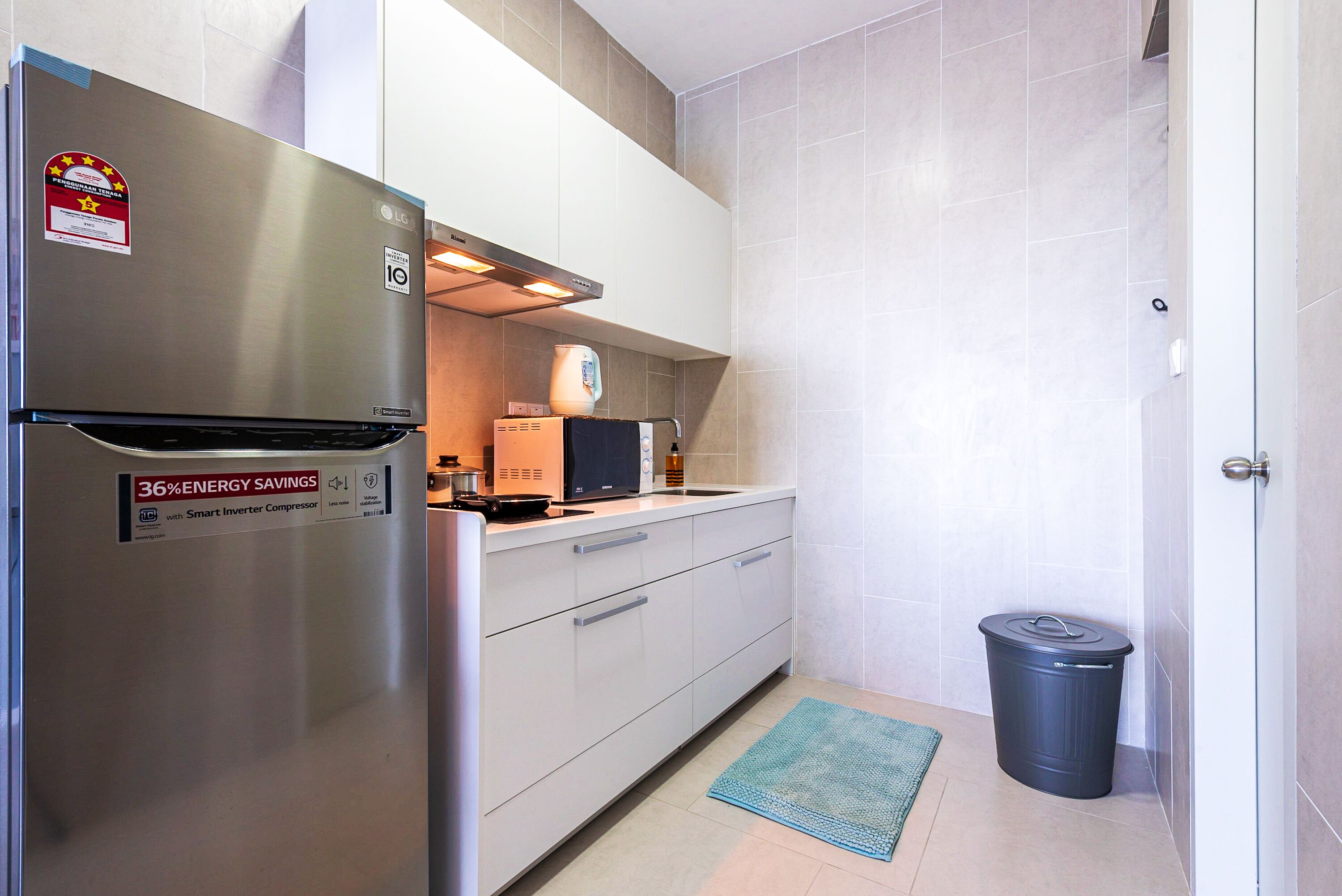 A compact kitchen with a stainless steel refrigerator, a microwave, and a toaster.