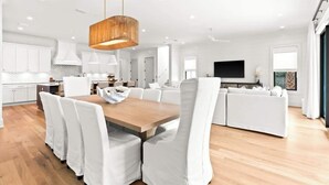 A modern kitchen with white cabinets, a wooden dining table, and a hanging light fixture. - 169 Lakeview Drive (Santa Rosa Beach)
