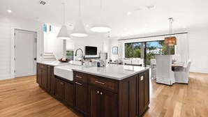 A modern kitchen with a large island, dark wooden cabinets, white countertops, and pendant lighting. - 169 Lakeview Drive (Santa Rosa Beach)