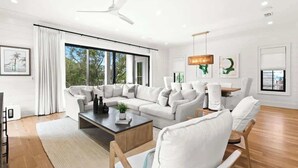 A modern living room with a sectional sofa, a coffee table, and a dining area. - 169 Lakeview Drive (Santa Rosa Beach)