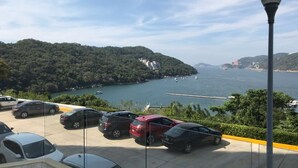 Un aparcamiento con coches y vistas a un lago y colinas.