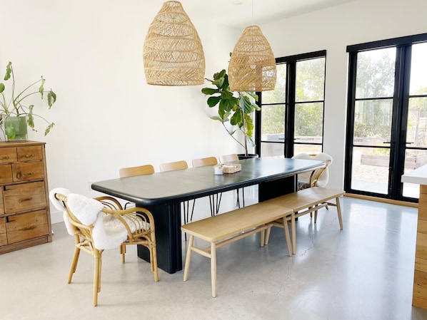 Guests can dine in style with a long table set for six, surrounded by comfortable chairs and pendant lights.