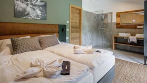 Une chambre d’hôtel avec un grand lit, un espace douche et une salle de bain équipée d’un miroir et d’un lavabo.