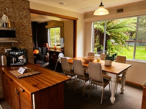 Una cocina con cafetera, estufa y comedor con sillas y mesa.