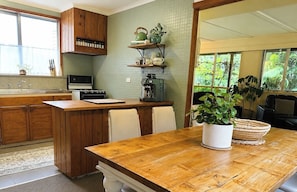 A kitchen with wooden cabinets, a stove, a coffee maker, and a dining area with a table and chairs.