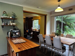 A cozy kitchen with a wood-burning stove, a coffee machine, and a dining area with chairs and a table.