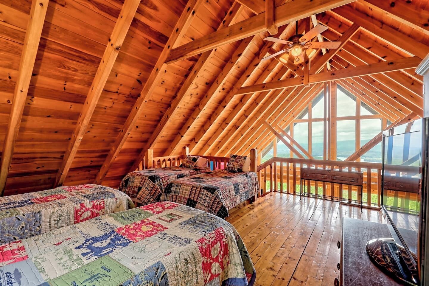 Une chambre confortable située dans les combles, avec des poutres apparentes, une grande fenêtre et une terrasse en bois.