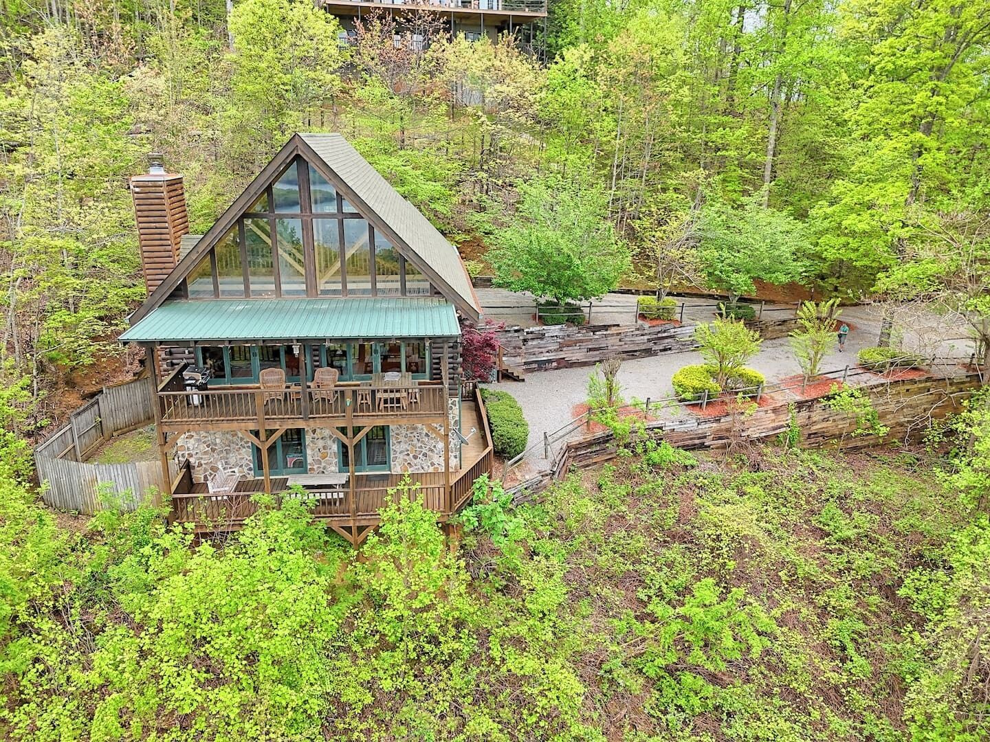 Eine Blockhütte mit Balkon und Natursteinfundament, umgeben von dichtem Wald.